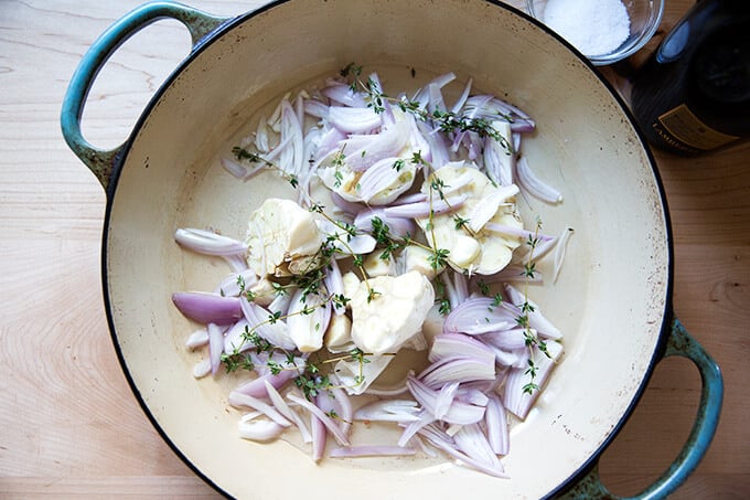 A braiser pan filled with shallots, garlic, thyme.