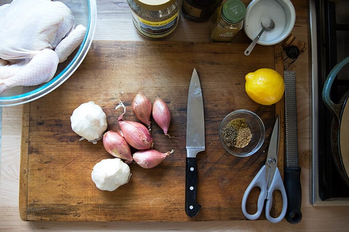 A cutting board with shallots, garlic, seasonings — the ingredients for spatchcock chicken with lemon and za'atar.