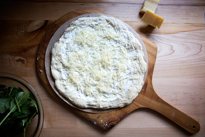 A round of pizza dough topped with creme fraiche, parmesan, and garlic.