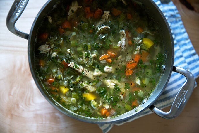 An overhead shot of a pot of homemade chicken soup with fregola. 