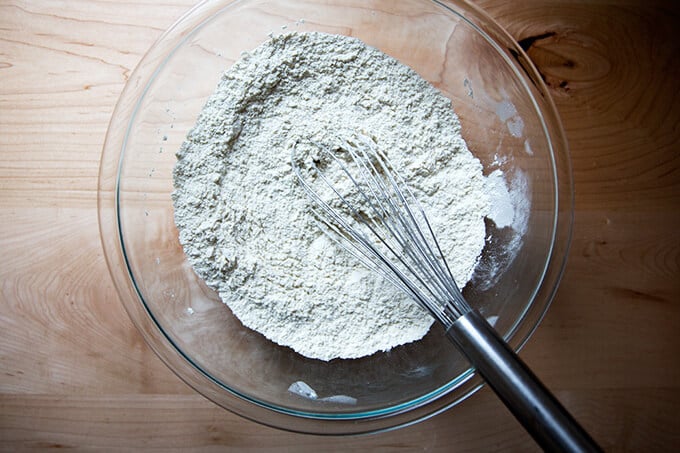 A bowl with a whisk, flour, salt, and yeast.
