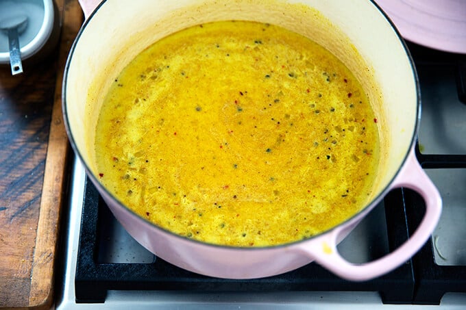 The curry liquids simmering in a dutch oven stovetop. 