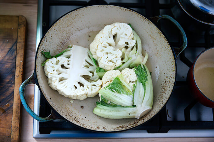 frying the cauliflower steaks in a large braiser stovetop