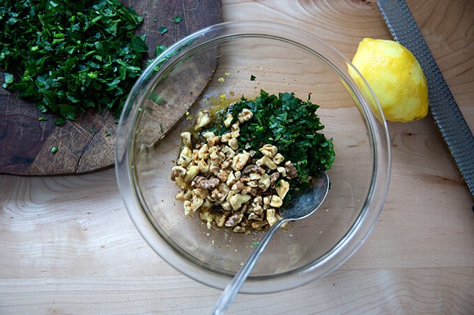 stirring together the walnut-caper salsa in a small glass bowl