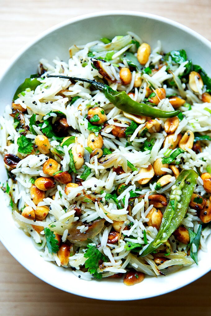 A bowl of Indian fried rice with peanuts and chilies.