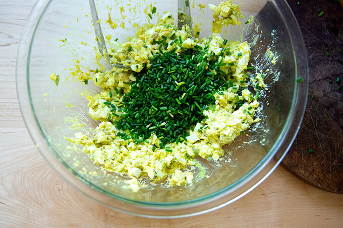Adding the chives to the bowl of hard-boiled eggs and avocado.