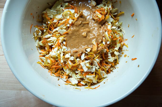 Adding the peanut dressing to the cabbage, carrots, and beets.