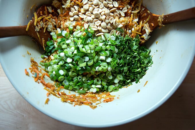 Adding the scallions, cilantro, and peanuts to the bowl of cabbage.