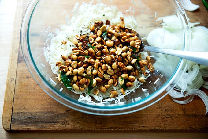 A bowl of rice, lime, peanuts and curry leaves.