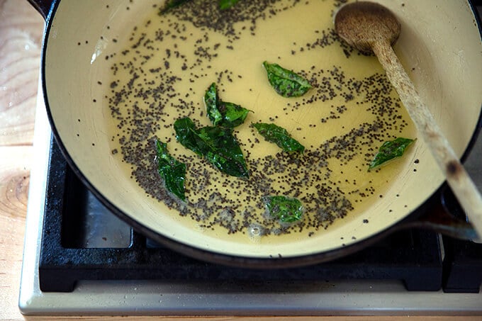 A braiser pan with ghee, mustard seed and curry leaves.