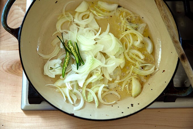 A braiser pan with ghee, onions, and chilies.