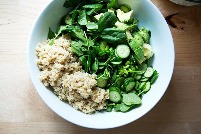 A bowl of brown rice, spinach, edamame, cucumber, and avocado.