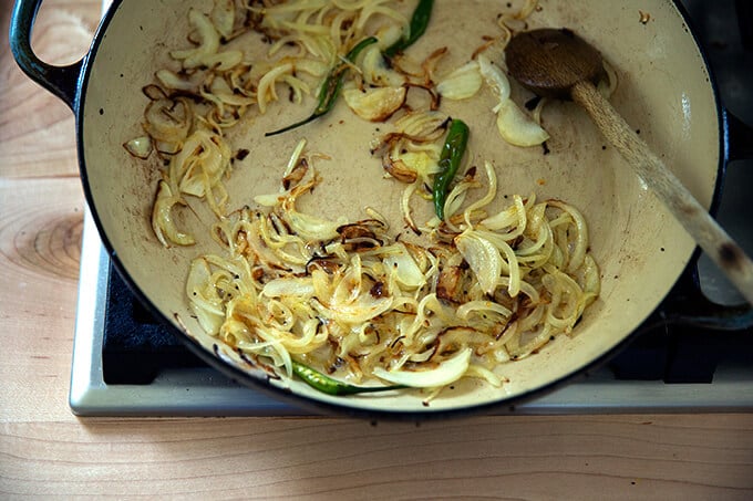 A braiser pan with sautéed onions and chilies.
