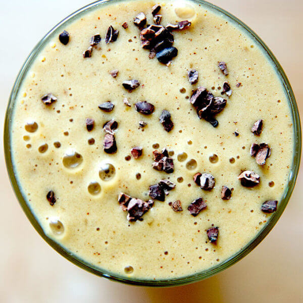 A glass filled with a coffee smoothie made with dates, banana, cauliflower, almond milk, almond butter, and cacao nibs.