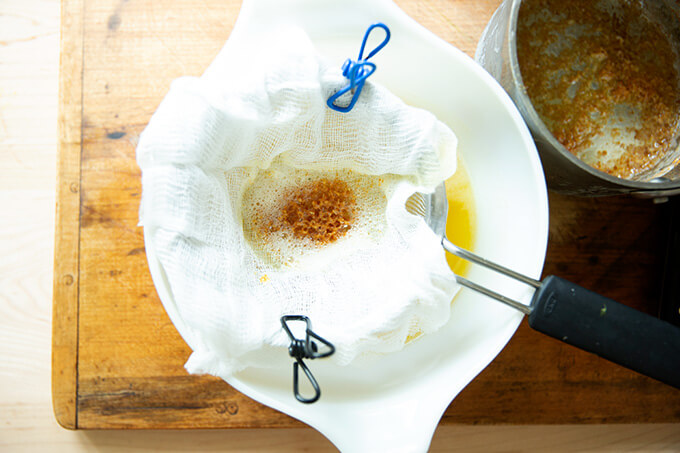 straining the ghee through cheesecloth into a bowl