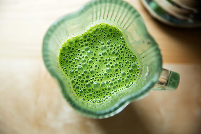 A blender filled with green smoothie, finished blending. 