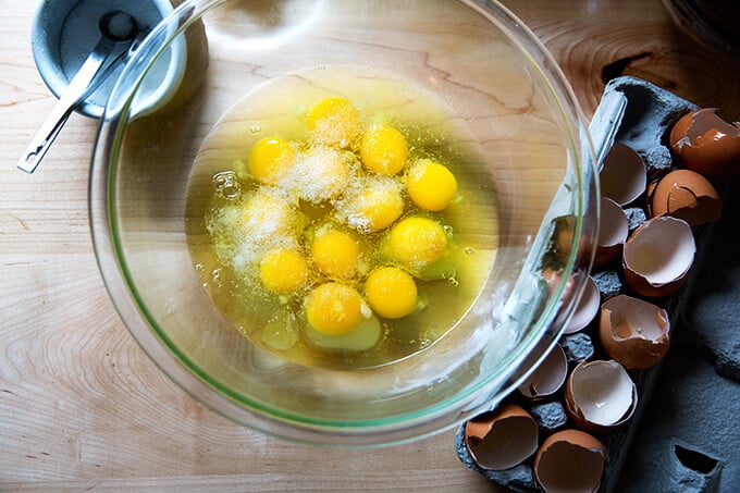 12 cracked eggs in a bowl with salt