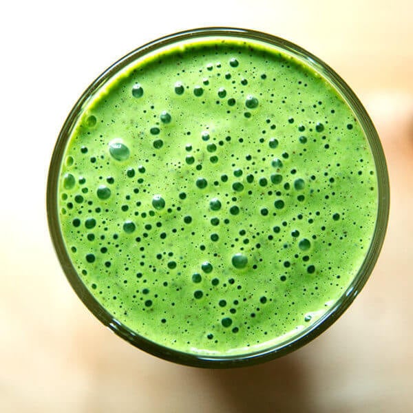 Overheaad shot of vegan green smoothie with almond milk, banana, and spinach.