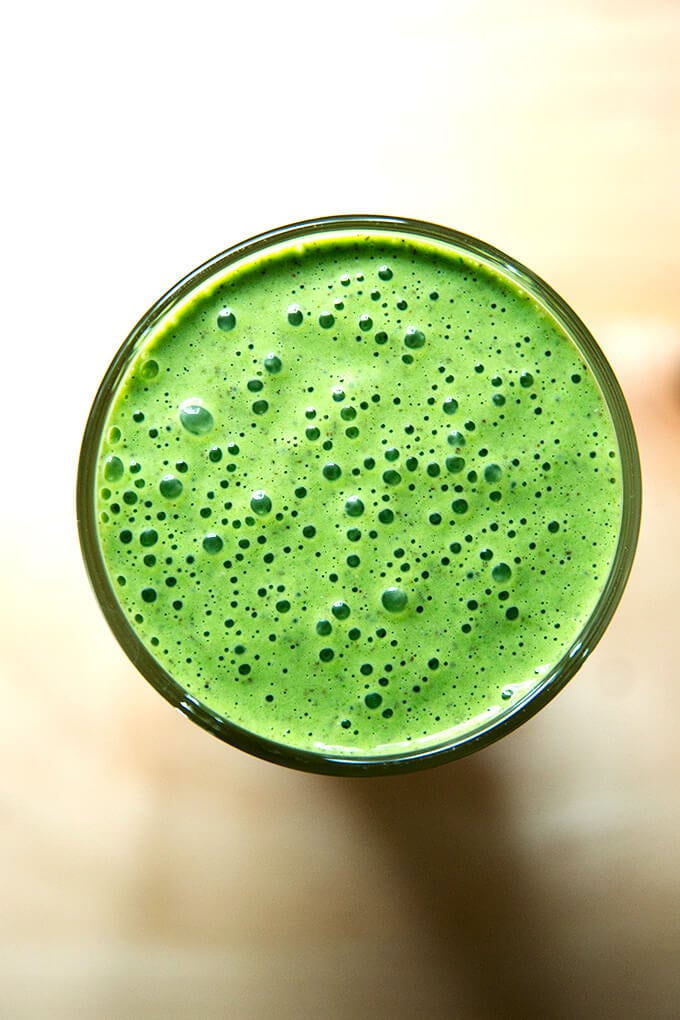 Overheaad shot of vegan green smoothie with almond milk, banana, and spinach.