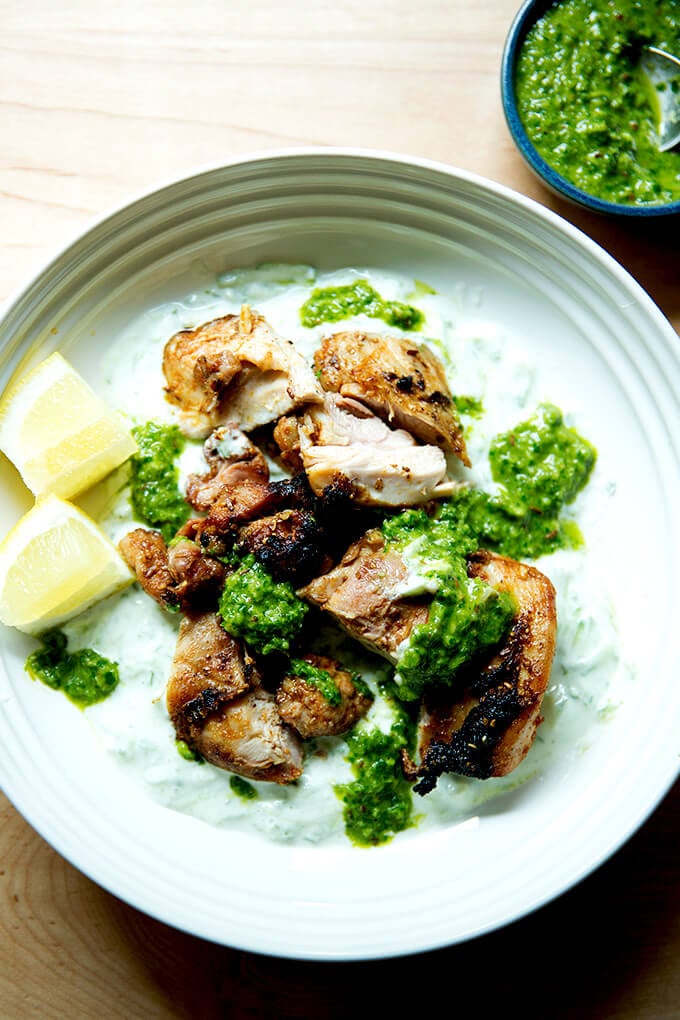 A platter of grilled, smoky chicken, cucumber-yogurt sauce,, skhug and lemon