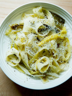 A bowl of braised leek pappardelle with grated parmesan over top.