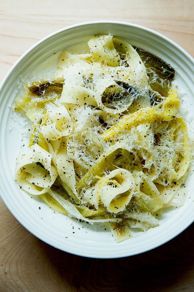 A bowl of braised leek pappardelle with grated parmesan over top.