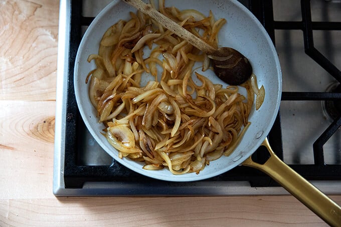 Onions caramelizing in a pan stovetop.