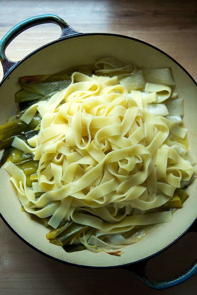 A braising pan filled with braised leeks and cooked pappardelle