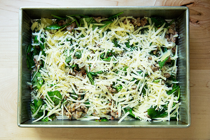 A 9x13-inch pan with sausage, spinach, cheese, and caramelized onions.