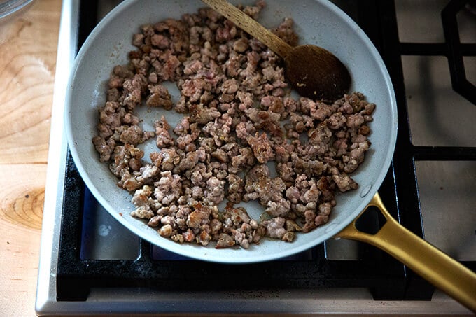 Hot Italian sausage browning in a pan stovetop.