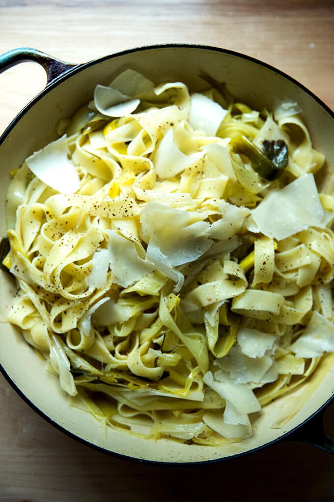 A braising pan filled with braised leeks, pappardelle, and shaved parm.