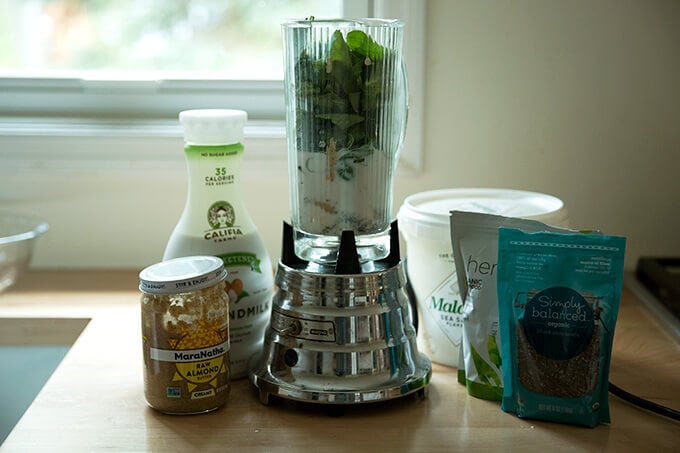 All of the ingredients for the green smoothie on the counter ready to be blended in the blender. 