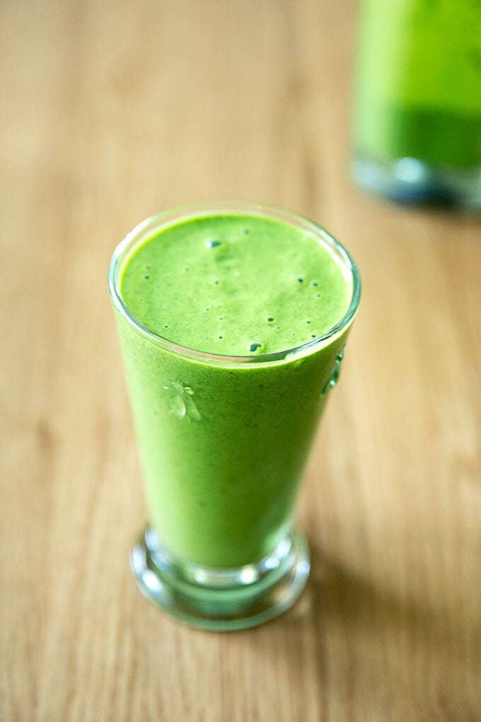 A tall glass filled with a green smoothie.