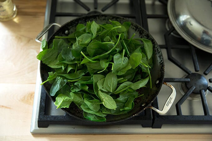 A skillet with lentils, onions, and a heap of spinach.