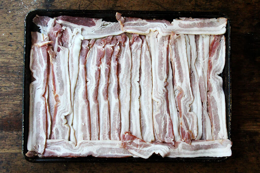 sheet pan loaded with uncooked bacon