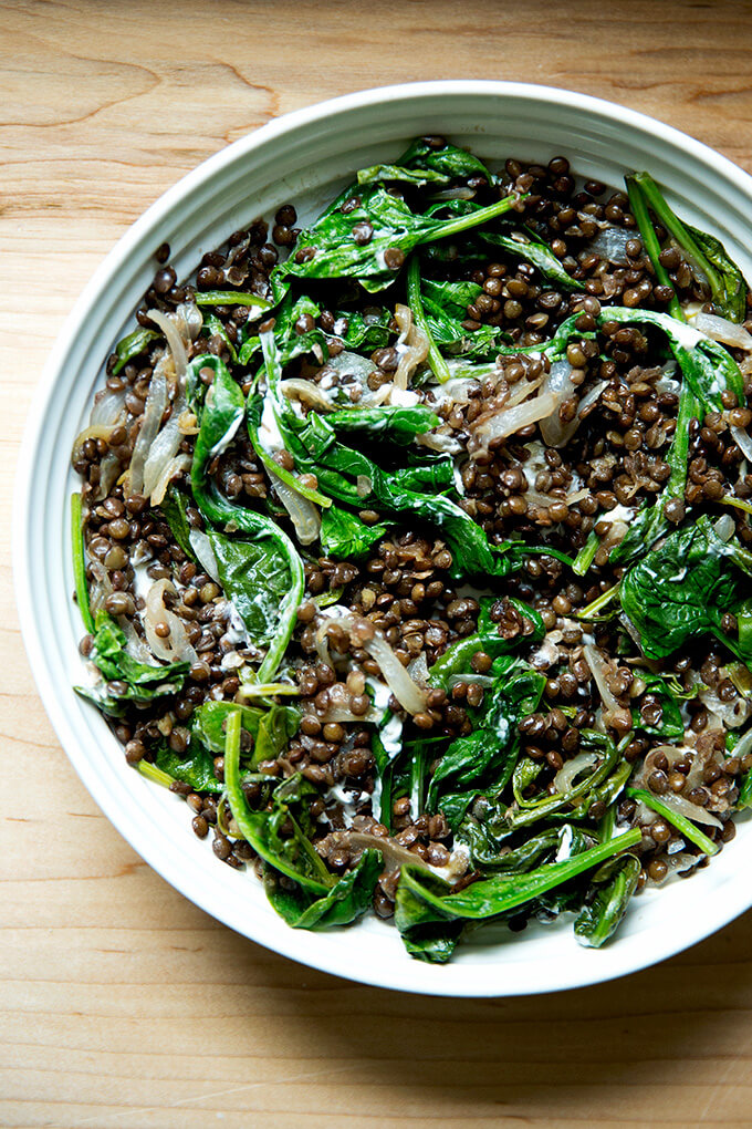 A bowl of black lentils with spinach and labneh.