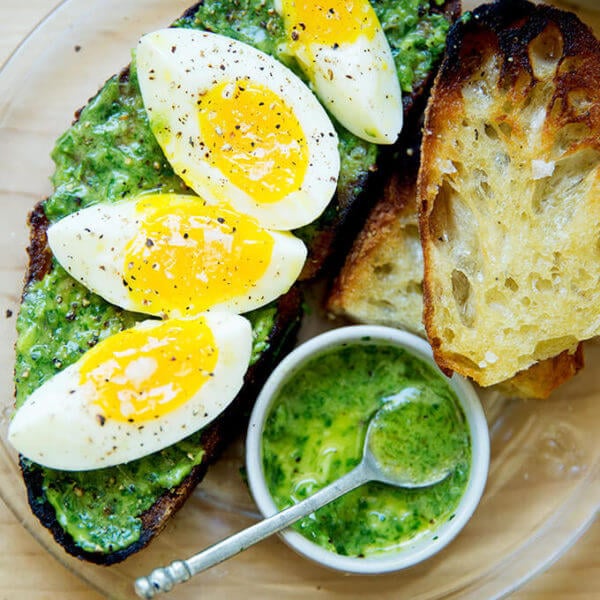 A plate of toasted sourdough smeared with green sauce, topped with 7-minute eggs.