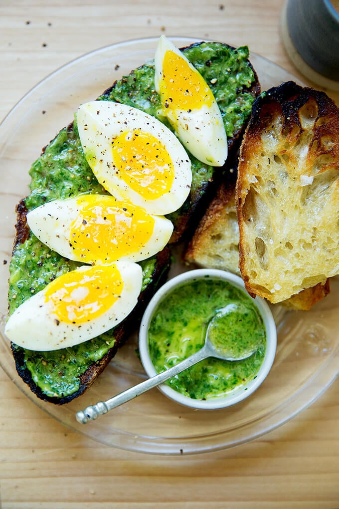 A plate of toasted sourdough smeared with green sauce, topped with 7-minute eggs.