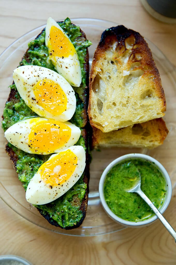 A plate of toasted sourdough bread with green sauce, and 7-minute eggs.