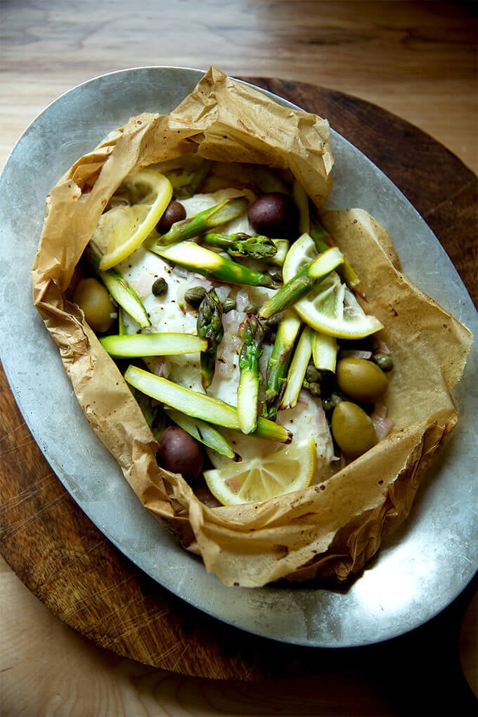 A sizzle pan with an opened fish en papillote.
