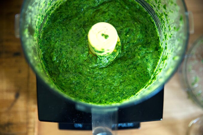 A food processor holding the puréed green sauce.