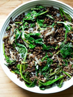 A bowl of black lentils with spinach and labneh.