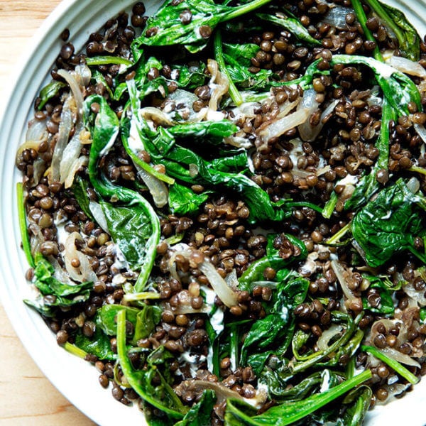 A bowl of black lentils with spinach and labneh.