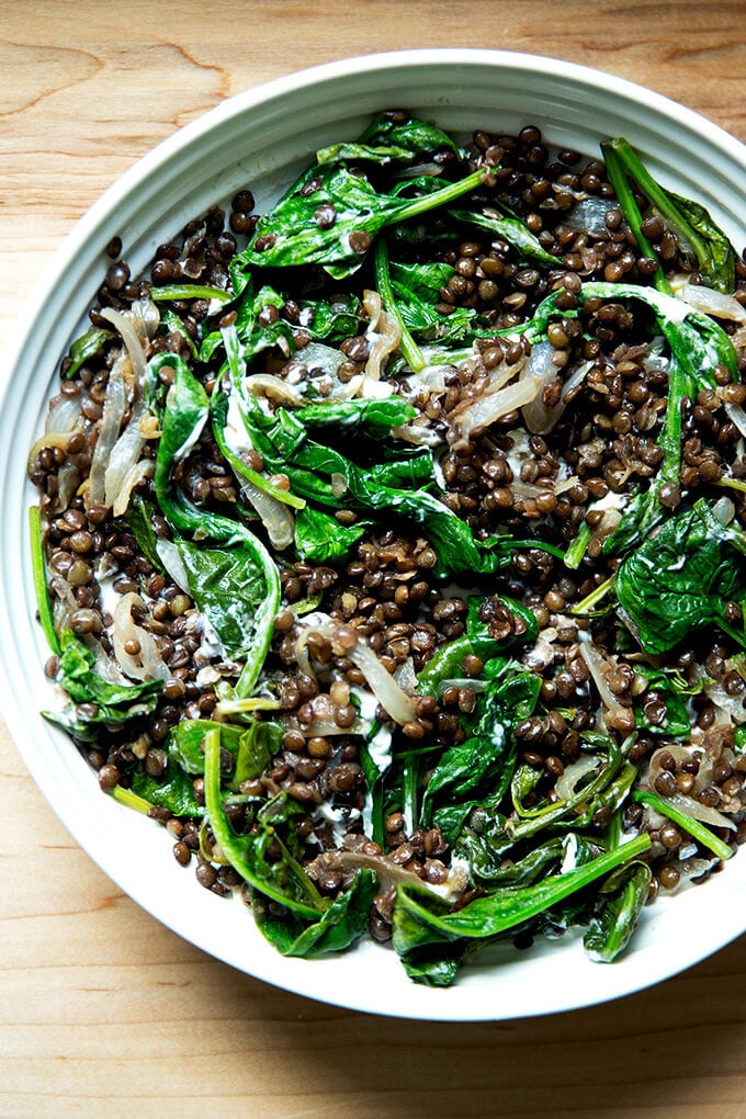 A bowl of black lentils with spinach and labneh.