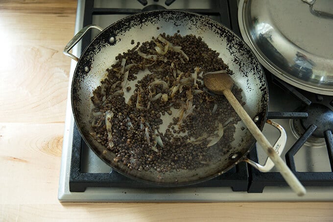 A skillet with lentils and onions.