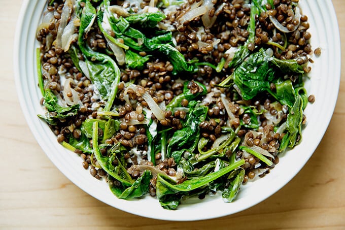 A bowl of black lentils with spinach and labneh.