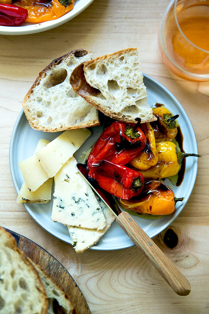 A plate of roasted peppers, cheese, and sourdough.