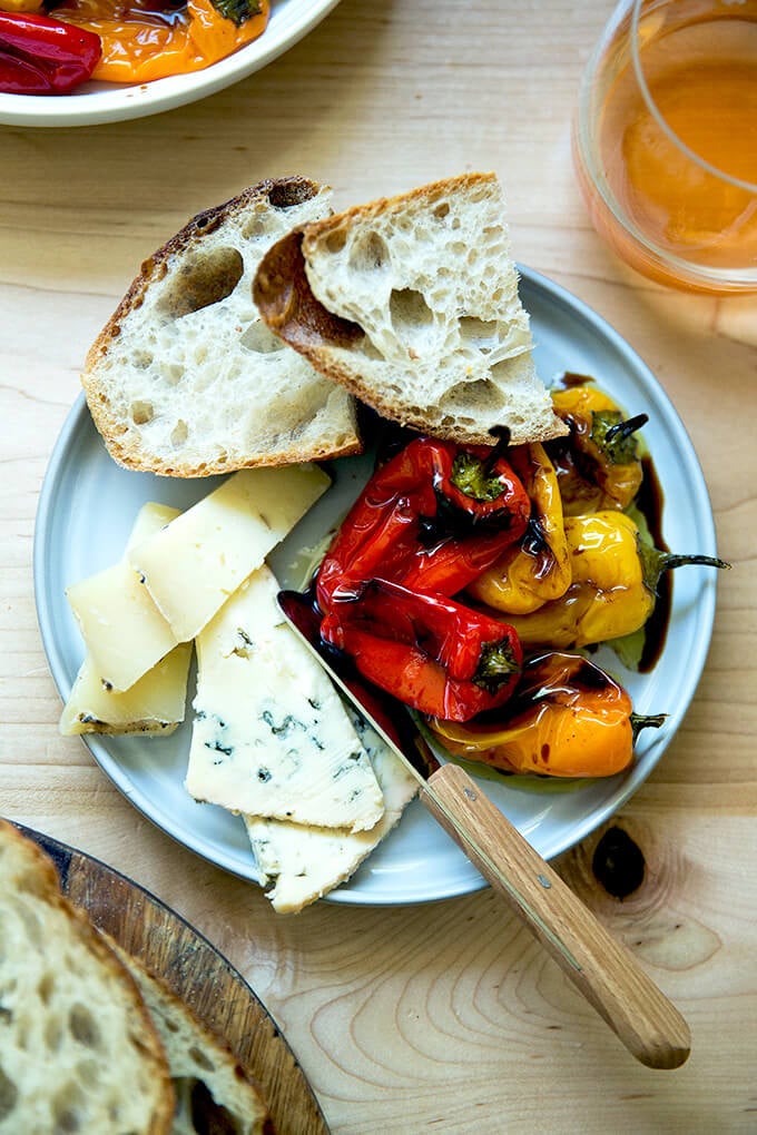 A plate of roasted peppers, cheese, and sourdough.