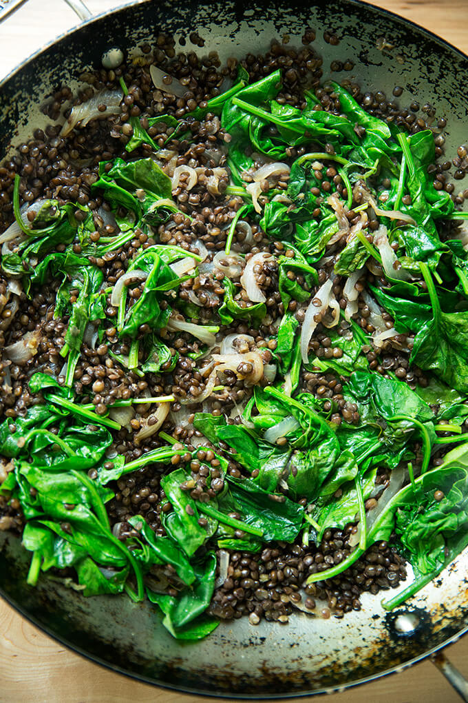 A skillet with finished lentils and spinach.