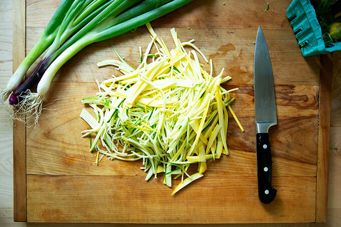 A board with thinly sliced zucchini. 